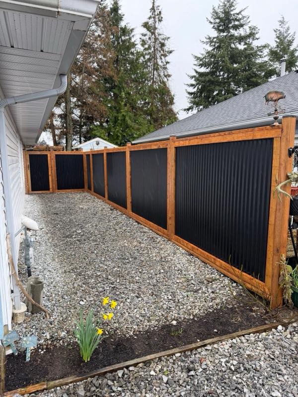 Long run of corrugated metal fence with cedar posts