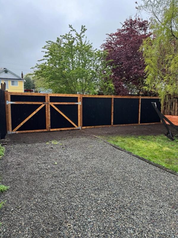 Cross-braced double swing gate beside a black metal fence